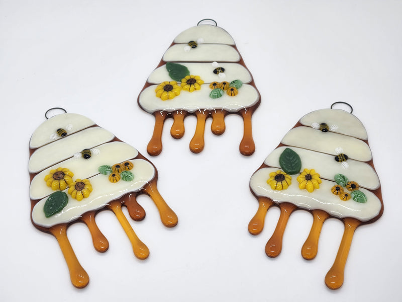 Three matching glass be hives flowing with honey and on the front of it has yellow flowers and bees.
