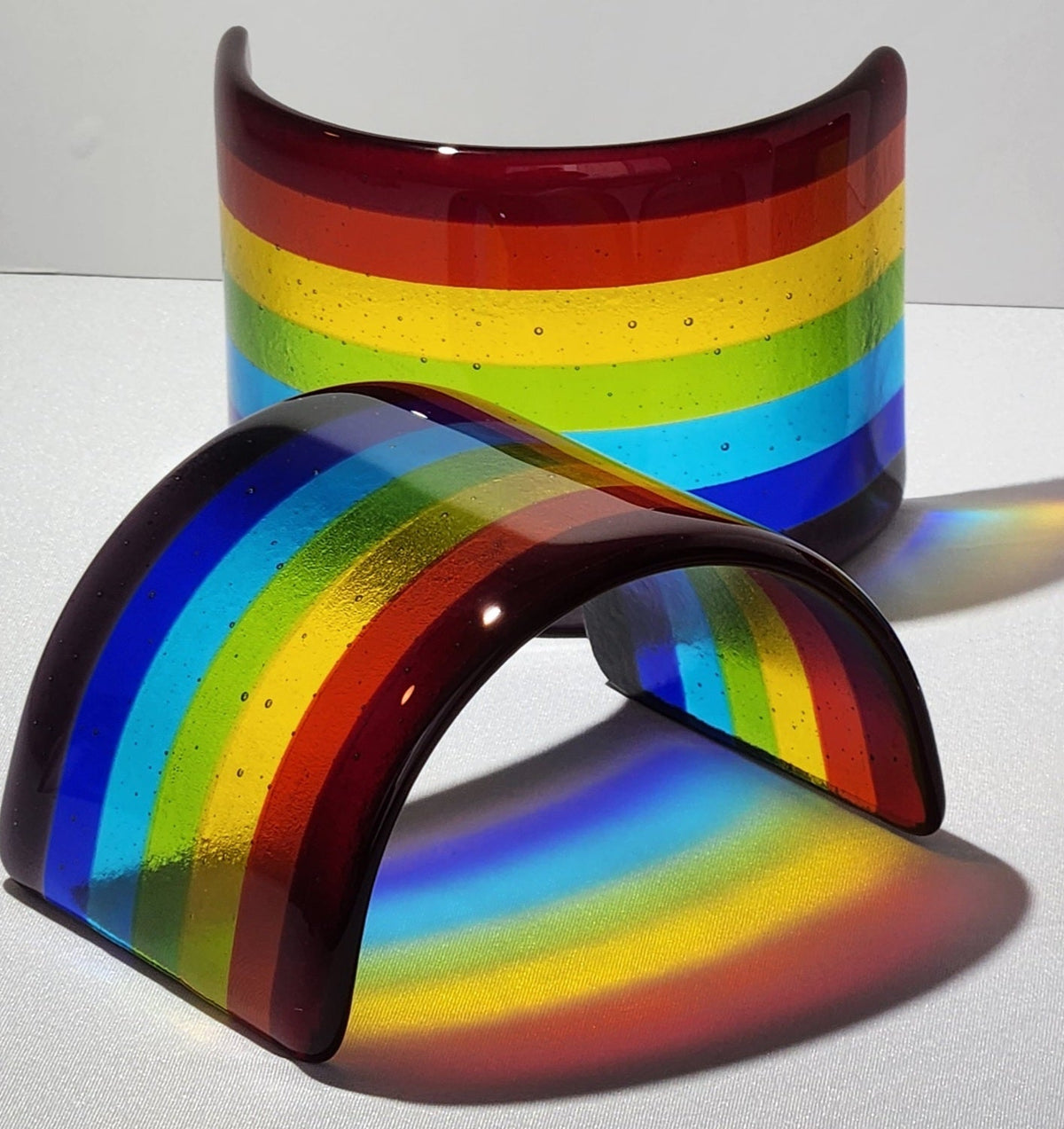 Fused glass Rainbow with vibrant bands of red, orange, yellow, green, blue, and purple that catch the sunlight and create colorful reflections for home decor.