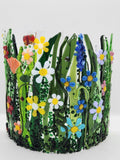 Curved fused glass Field of Flowers candle holder with colorful wildflowers, green grass, butterflies, bees, and ladybugs, designed to display beautifully with candlelight.