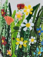 Curved fused glass Field of Flowers candle holder with colorful wildflowers, green grass, butterflies, bees, and ladybugs, designed to display beautifully with candlelight.