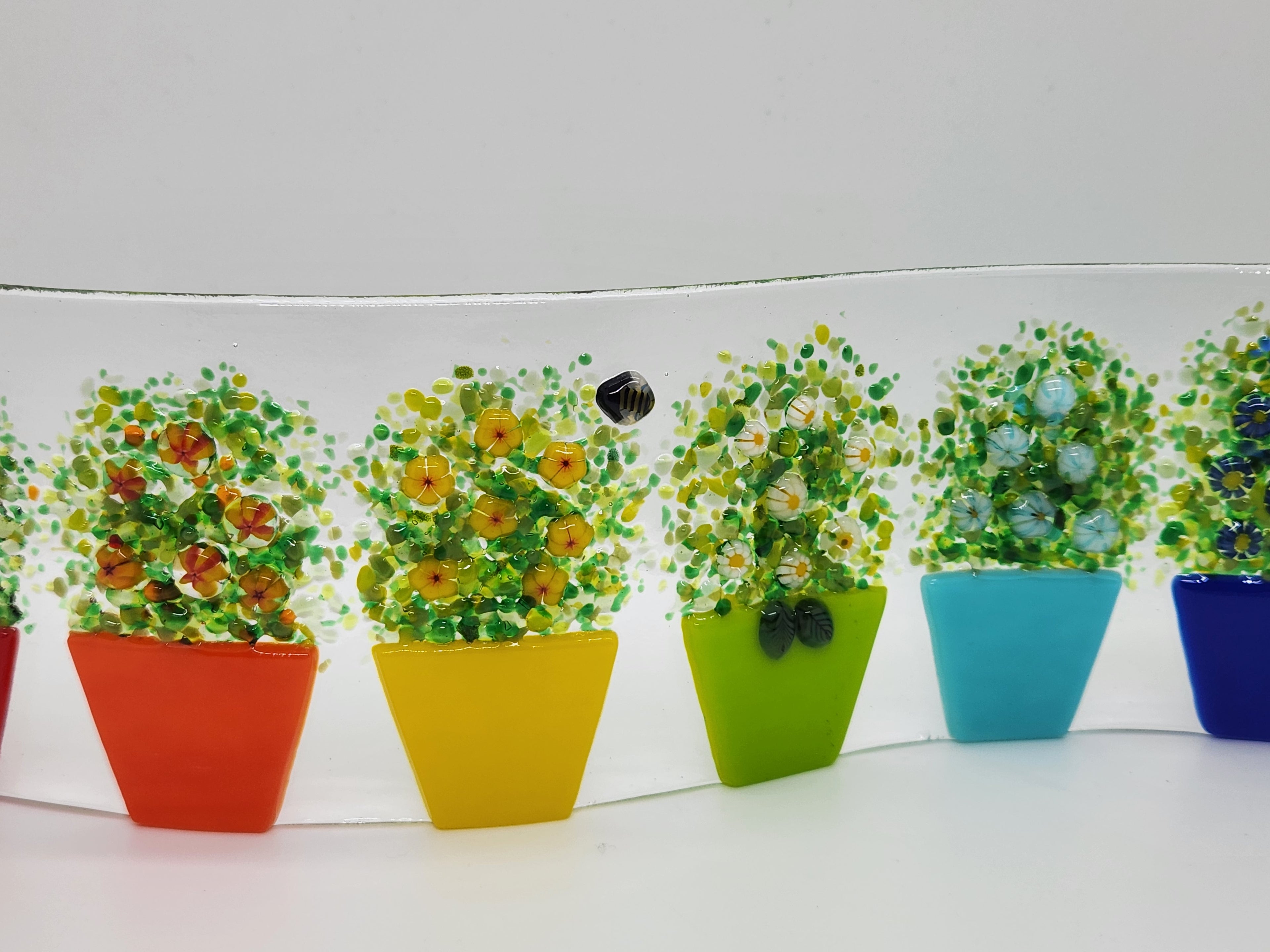 Fused glass Flower Pot Waves featuring rainbow flower pots with blooming greenery on a gently curved glass panel for home decor.