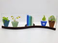 Fused glass Book Shelf Wave featuring colorful books, potted plants, and garden-inspired details on a gently curved glass panel for home decor.