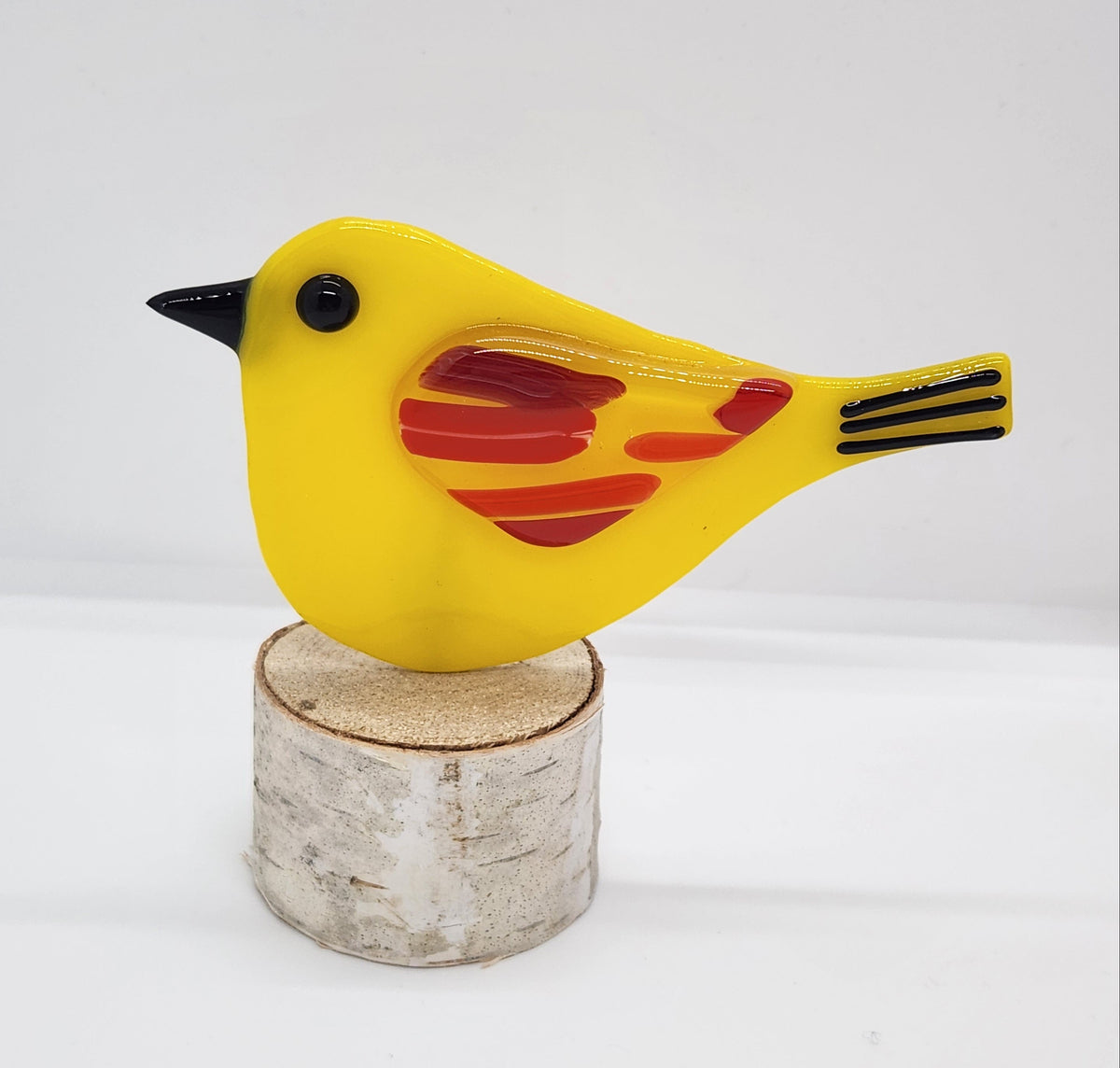 Yellow songbird on birch wood stand