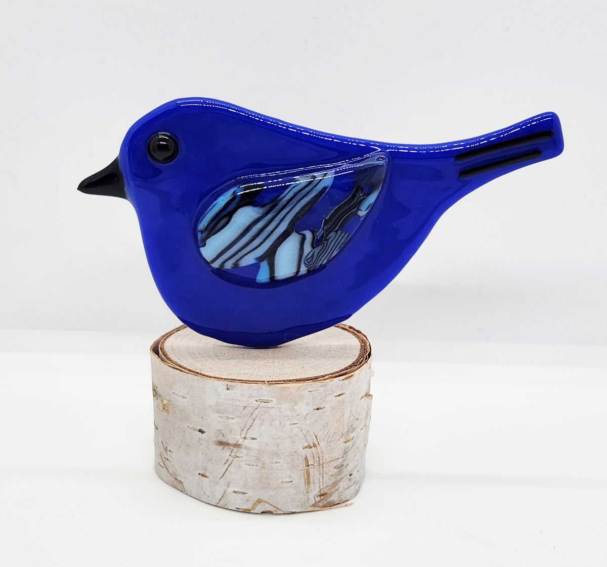 Dark blue songbird on birch wood stand