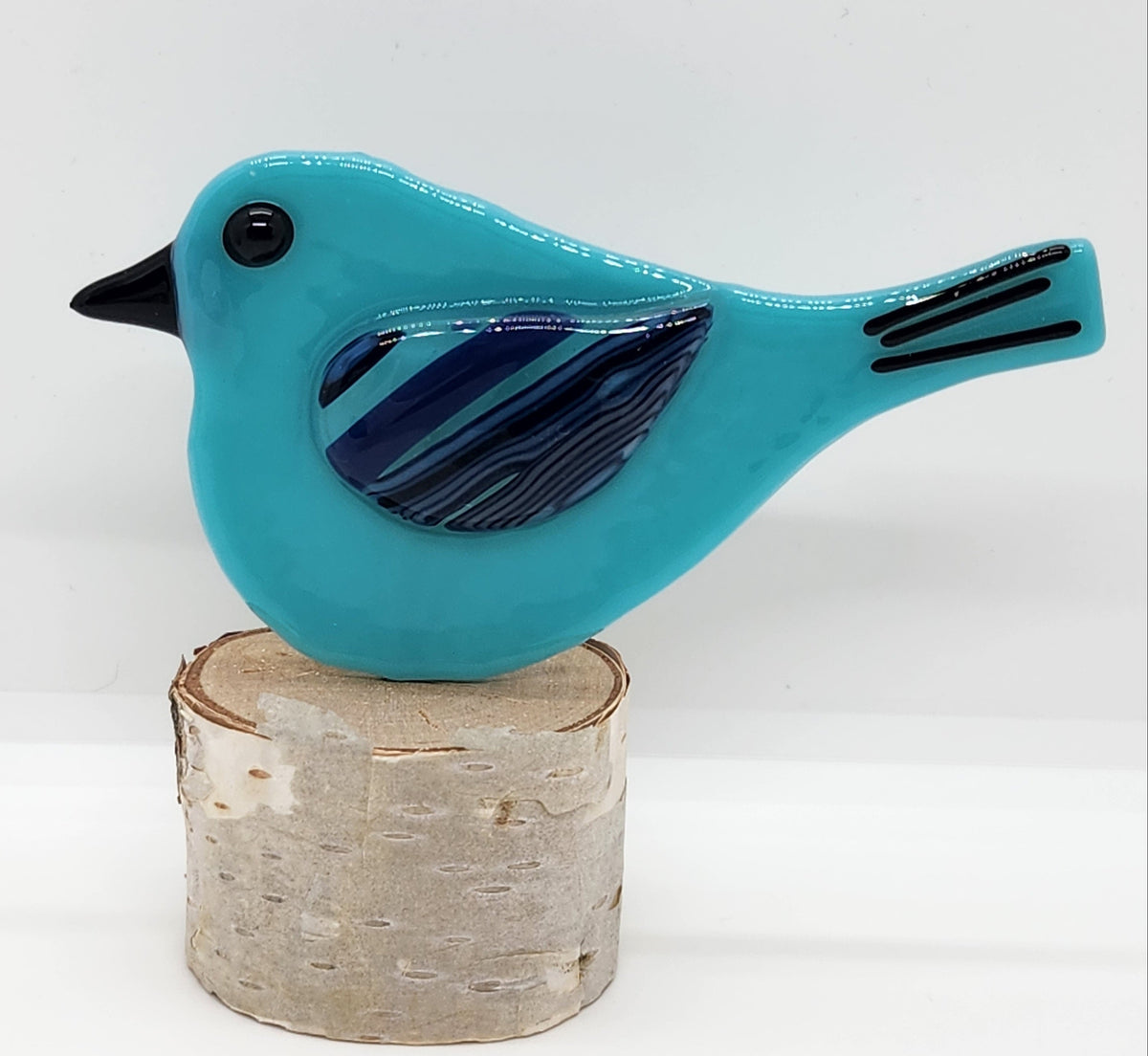 Blue songbird on birch wood stand