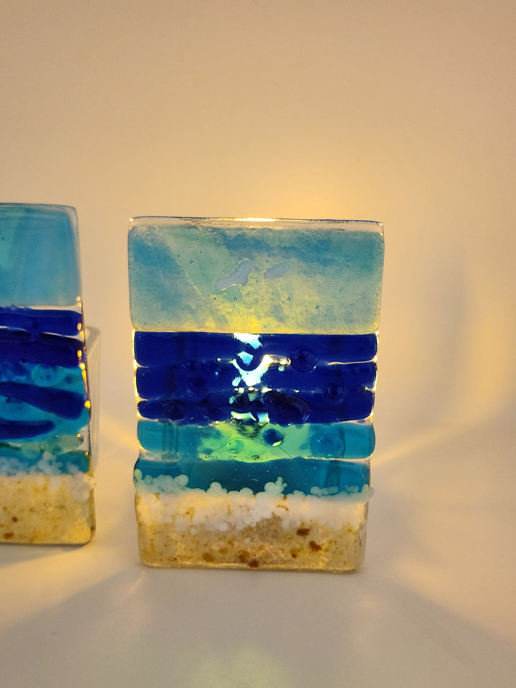Fused glass Ocean Aqua candle holder with layered aqua, deep blue, and sandy glass, inspired by the colors of the shoreline and designed for home decor.