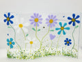 Fused glass floral panel featuring lavender, turquoise, white, and blue daisies with whimsical garden details and a gently curved design for home decor.
