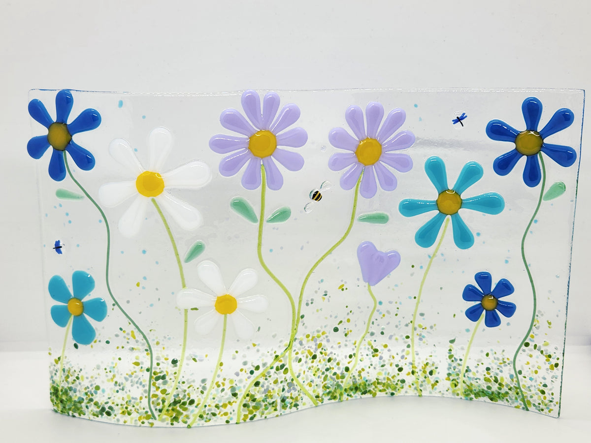 Fused glass floral panel featuring lavender, turquoise, white, and blue daisies with whimsical garden details and a gently curved design for home decor.