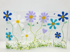 Fused glass floral panel featuring lavender, turquoise, white, and blue daisies with whimsical garden details and a gently curved design for home decor.