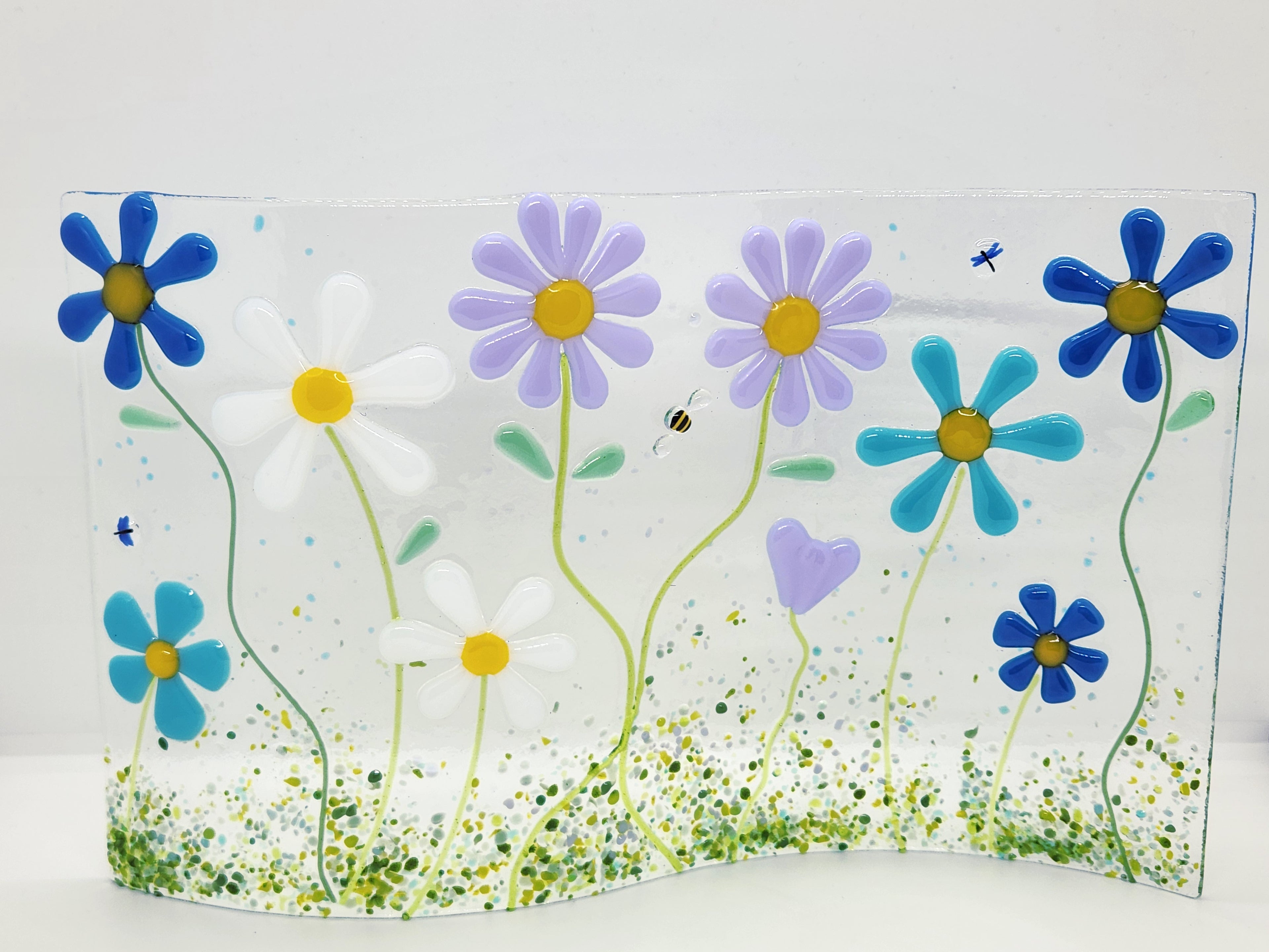 Fused glass floral panel featuring lavender, turquoise, white, and blue daisies with whimsical garden details and a gently curved design for home decor.