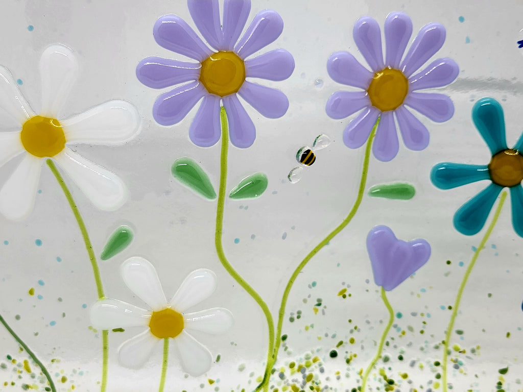 Fused glass floral panel featuring lavender, turquoise, white, and blue daisies with whimsical garden details and a gently curved design for home decor.