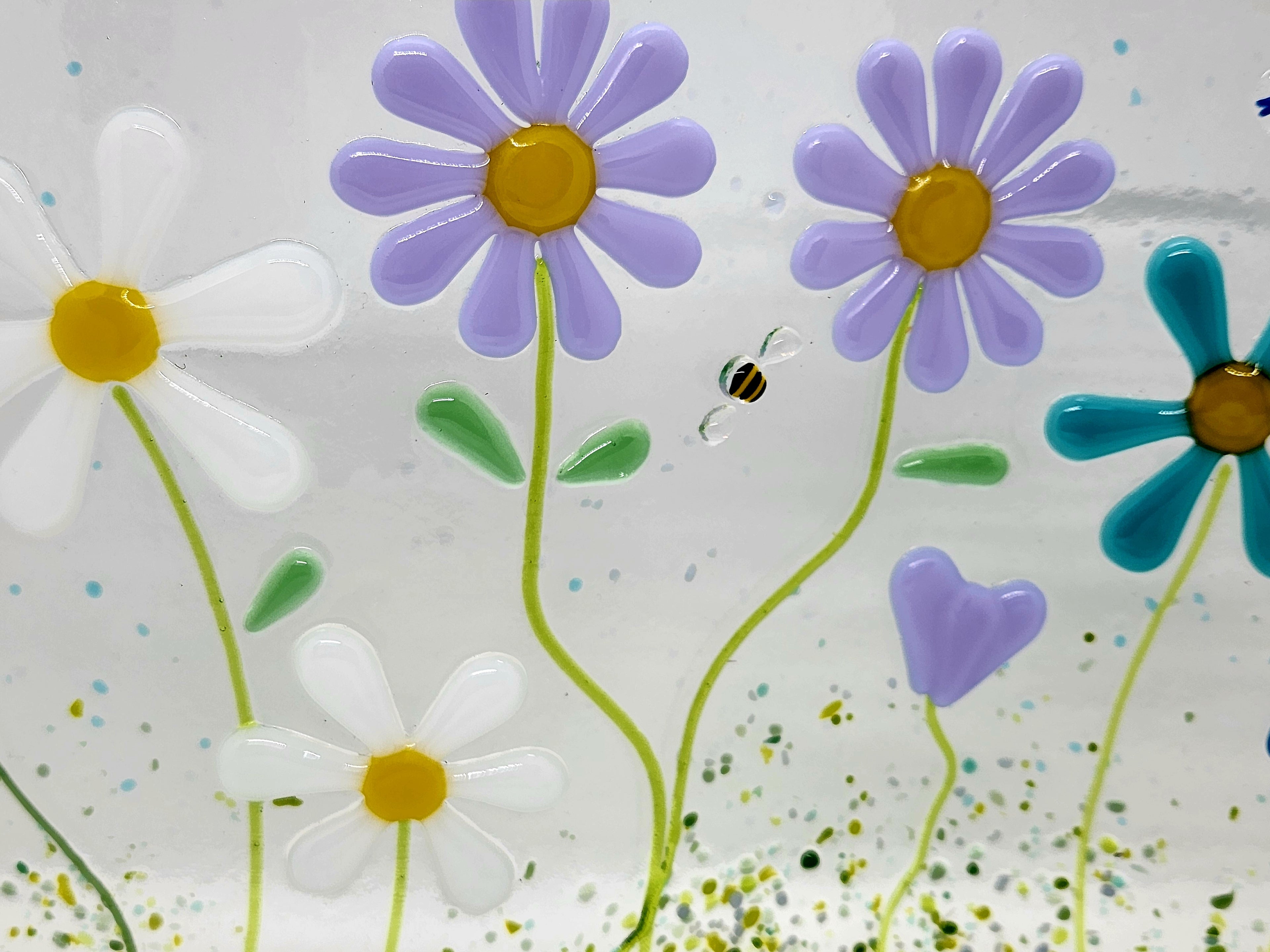 Fused glass floral panel featuring lavender, turquoise, white, and blue daisies with whimsical garden details and a gently curved design for home decor.
