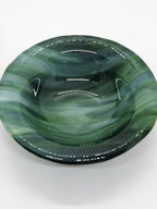 A small oval green glass dish with swirling marbled patterns in shades of green, black, and white.