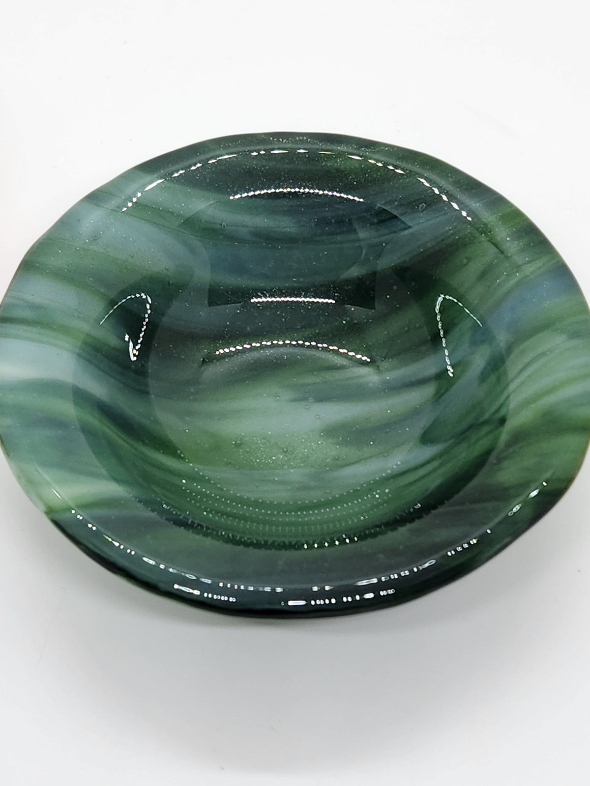A small oval green glass dish with swirling marbled patterns in shades of green, black, and white.