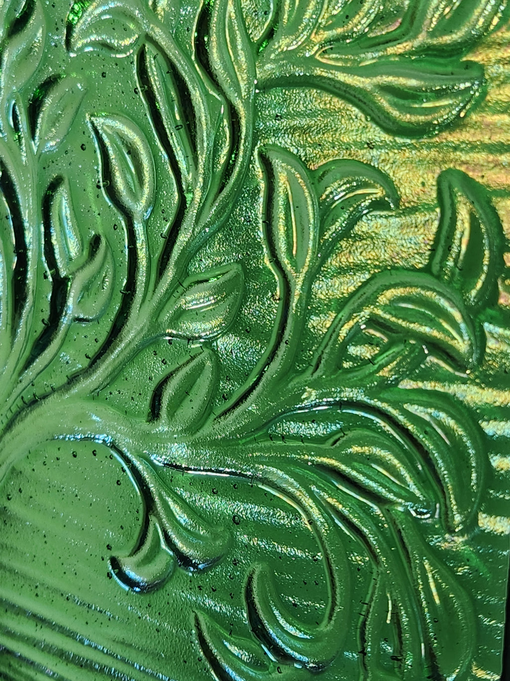 A close up of a square glass art panel featuring the tree of life which has green hues.