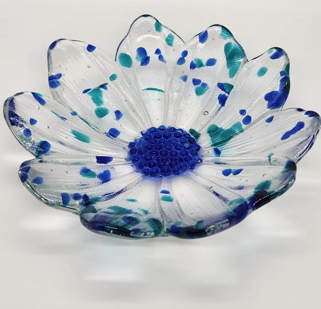 clear glass flower with blue center and blue flecks of glass on  a white background