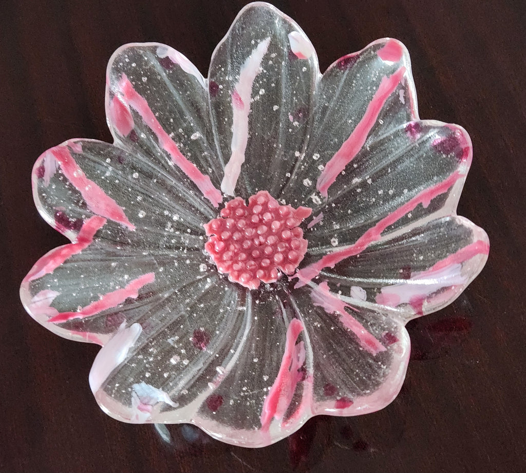 a flower shaped glass bowl on a dark brown surface.