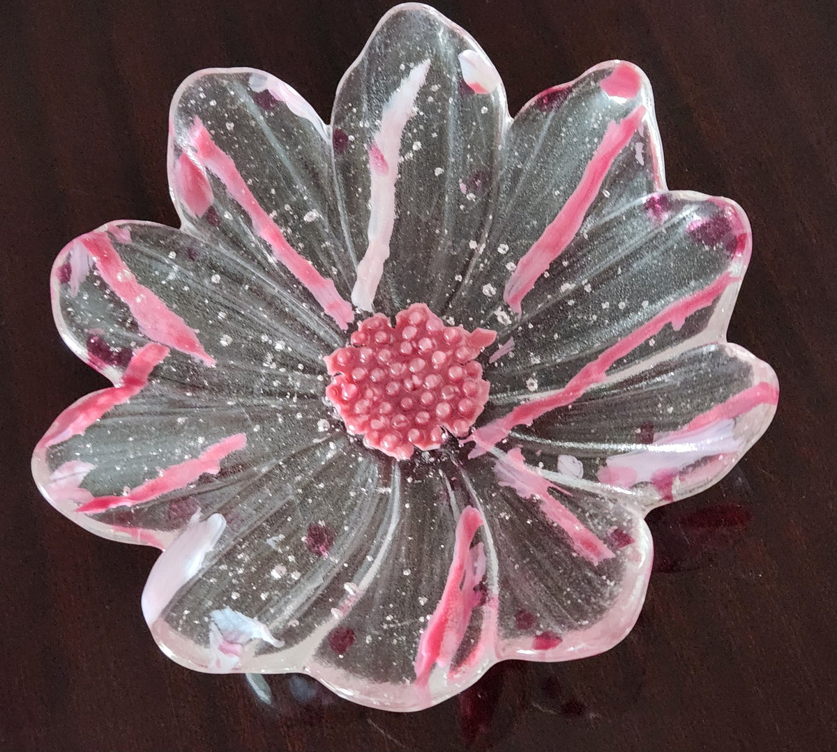 a flower shaped glass bowl on a dark brown surface.