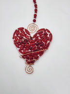 Red heart suncatcher wrapped in copper wire with bead handle.